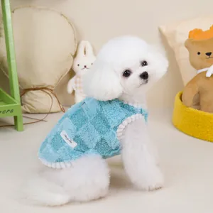 Detail of blue checkered plush pet vest featuring soft fleece texture and pom-pom trim