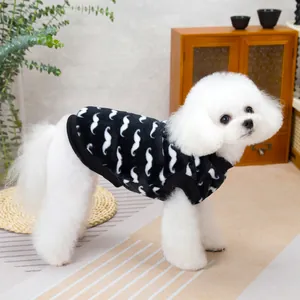 White poodle wearing a black velvet dog vest with white mustache prints in a cozy room