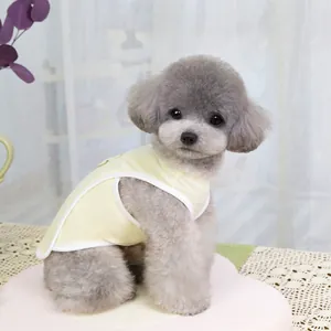Detailed view of light yellow breathable cotton pet vest with white trim on a grey poodle