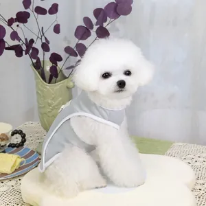 Detail of grey pet vest with white trim on a white dog, set against a floral background