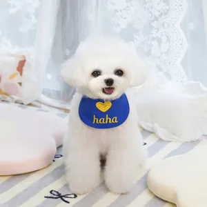 Detailaufnahme des blauen Haustier-Lätzchens mit gelbem Herz auf einem weißen Hund