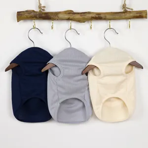 Tre gilet in maglia waffle per cani e gatti appesi a rami di legno naturale