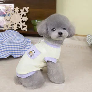 Detail of breathable yellow pet T-shirt with purple bear pocket on a grey poodle