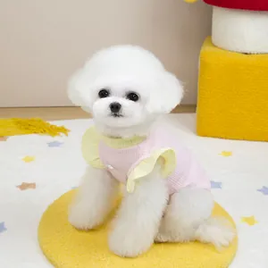 Detailed view of pink and yellow contrast knit vest with ruffles on a white dog