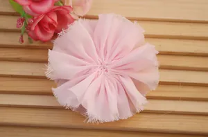 Detailed close-up of pink handmade chiffon flower headpiece with soft frayed petal edges
