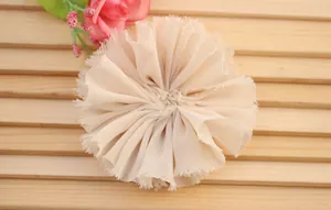 Macro detail of a beige chiffon handmade floral hair accessory with vintage frayed edges