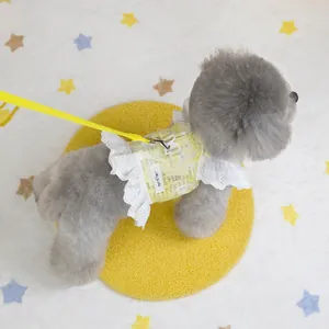 Close-up of a yellow newspaper print pet harness with white lace trim and metal D-ring