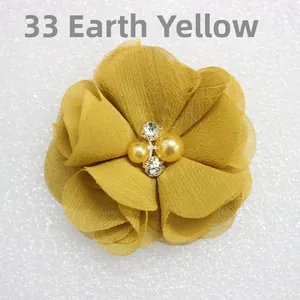 Detail of earthy yellow chiffon flower clip with elegant pearl and rhinestone center