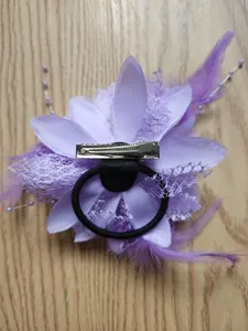 Dettaglio del fermaglio a fiore viola con clip a becco d'anatra e elastico per capelli nero