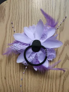 Dettaglio fermaglio fiore viola con piume, perline e rete su sfondo in legno