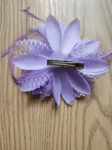 Vista dettagliata del retro di una molletta a fiore viola con piume e clip metallica