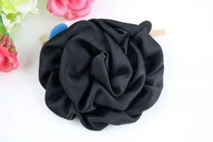 Détail d'un grand accessoire de cheveux rose en satin noir aux pétales superposés