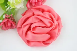 Vue détaillée d'une rose en tissu satiné rose avec des feuilles vertes