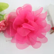 Close-up of a layered rose pink chiffon floral headband for girls on a white fence