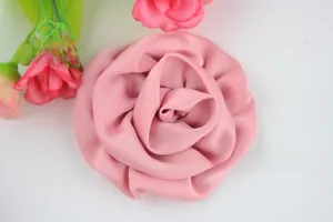 Vue détaillée d'un bouton de rose en tissu rose mat fait main avec pétales soyeux