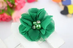 Detail of green chiffon flower hair clip featuring faux pearls and crystals center