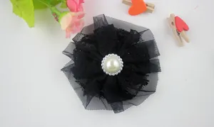 Detail of a black lace flower hair accessory featuring a creamy faux pearl centerpiece