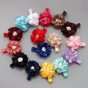 Flat lay of 15 colorful satin flower hair clips for babies in a spiral arrangement