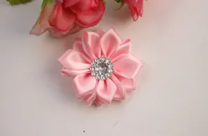 Macro detail of a pink satin handmade flower accessory with a central diamond rhinestone
