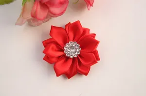 Macro detail of a handmade red satin fabric flower with a central rhinestone crystal core