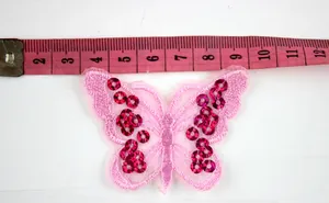 Detail of a 9cm light pink sequined butterfly embroidery patch with measurement tape