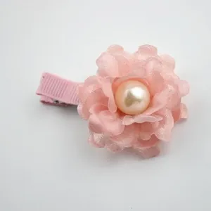 Detail of pink fabric flower hair clip with a cream pearl center and grosgrain ribbon base