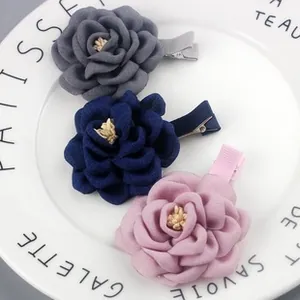 Macro detail of three chiffon fabric rose hair clips in grey, navy and pink tones