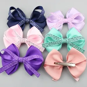 Detail of six colorful grosgrain ribbon bow clips with script print and metal alligator grips