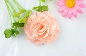 Handmade pink satin fabric rose flower with green leaves and realistic layered petals