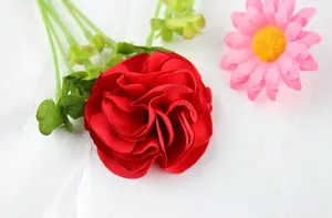 Detail of handmade red fabric rose with curled edges and green wire stem for DIY crafts
