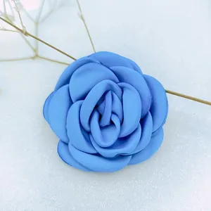 Macro view of blue fabric camellia flower with burnt edge and layered satin petals