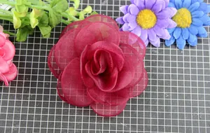 Dettaglio di una spilla a rosa in tessuto bordeaux multistrato in organza trasparente