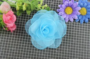 Vista dall'alto di fermaglio per capelli con rosa in rete azzurra e petali in organza
