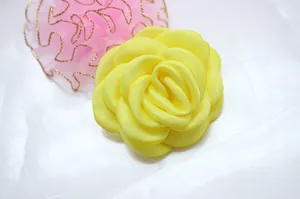 Macro view of handmade lemon yellow satin camellia flower with pink lace detail