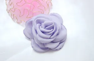 Macro detail of handmade lavender fabric camellia flower with layered satin petals