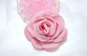 Close-up of pink fabric camellia flower with golden lace edge for hair accessories