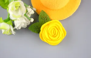 Primer plano detallado de un broche de rosa de fieltro amarillo hecho a mano con hojas