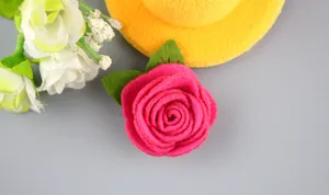Vista macro de rosa de fieltro rosa hecha a mano con hojas para accesorios de bricolaje