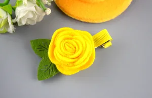 Détail d'une pince à cheveux rose en feutre jaune avec feuilles sur clip en tissu ruban