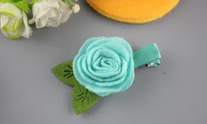 Détail d'une pince à cheveux rose en feutre bleu faite main avec feuilles vertes et ruban
