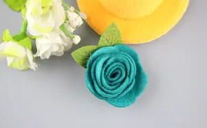 Vista detallada de una rosa de fieltro azul hecha a mano con hojas verdes y costuras