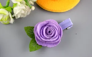 Détail d'une pince à cheveux rose en feutre violet avec feuilles et ruban assorti