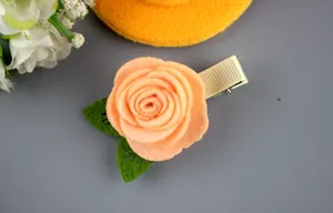 Détail d'une pince à cheveux rose en feutre pêche avec feuilles sur ruban crème
