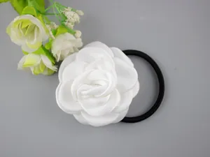 Detail of elegant white camellia hair scrunchie with silk fabric petals and black elastic band