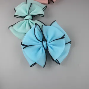 Detail of double-layer chiffon bow accessories with black stitched edges in pastel colors
