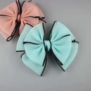 Large chiffon bow hair accessories in pink and mint green with black woven edges