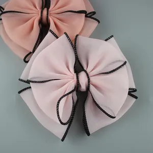 Detail of light pink chiffon bow with black woven edge trim for hair or shoe accessories
