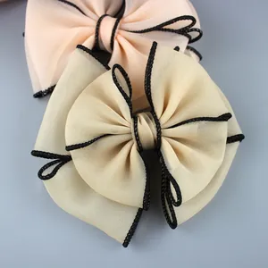 Close-up of double-layered chiffon bow hair accessory with black braided rope trim