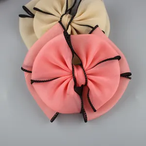 Detail of large multi-layer chiffon bow accessories with black stitched edges