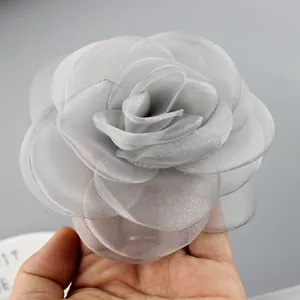 Dettaglio di una spilla a forma di rosa in pizzo grigio da 10 cm con strati di velo
